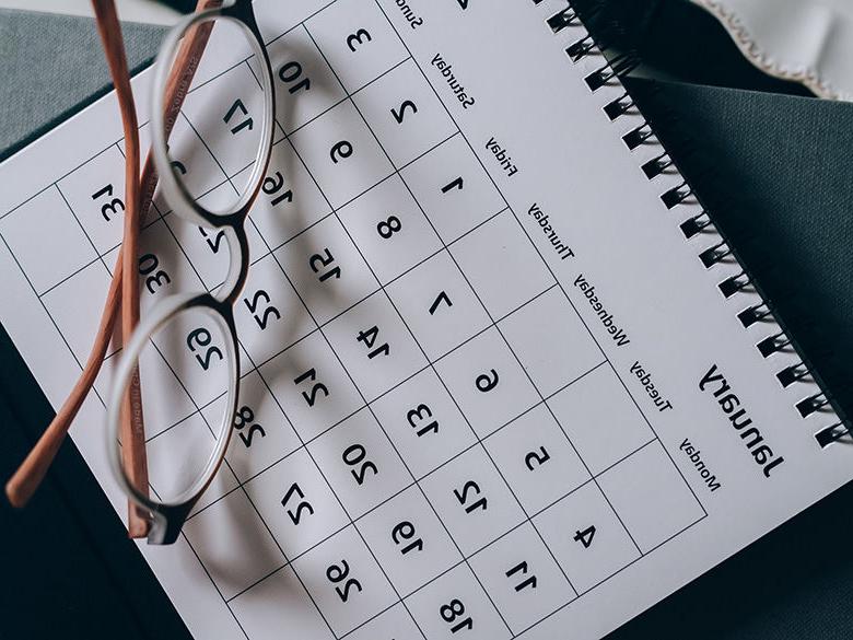 a calendar lying on a table with a pair of glasses resting on top of it