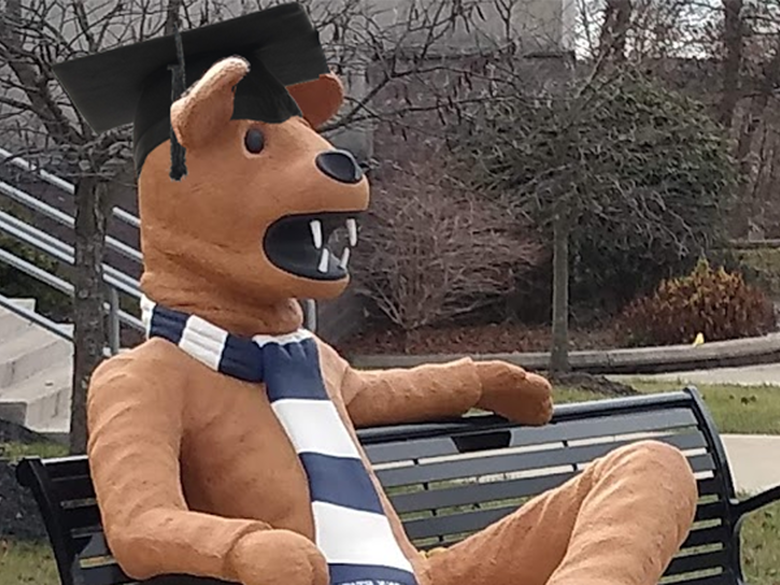 Nittany Lion statue wearing a mortarboard and sitting on bench in front of the Struthers Career Services Center