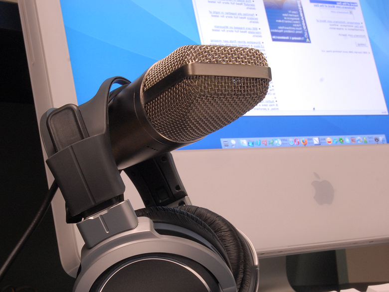a closeup of a microphone and headset with a Macintosh computer in the background